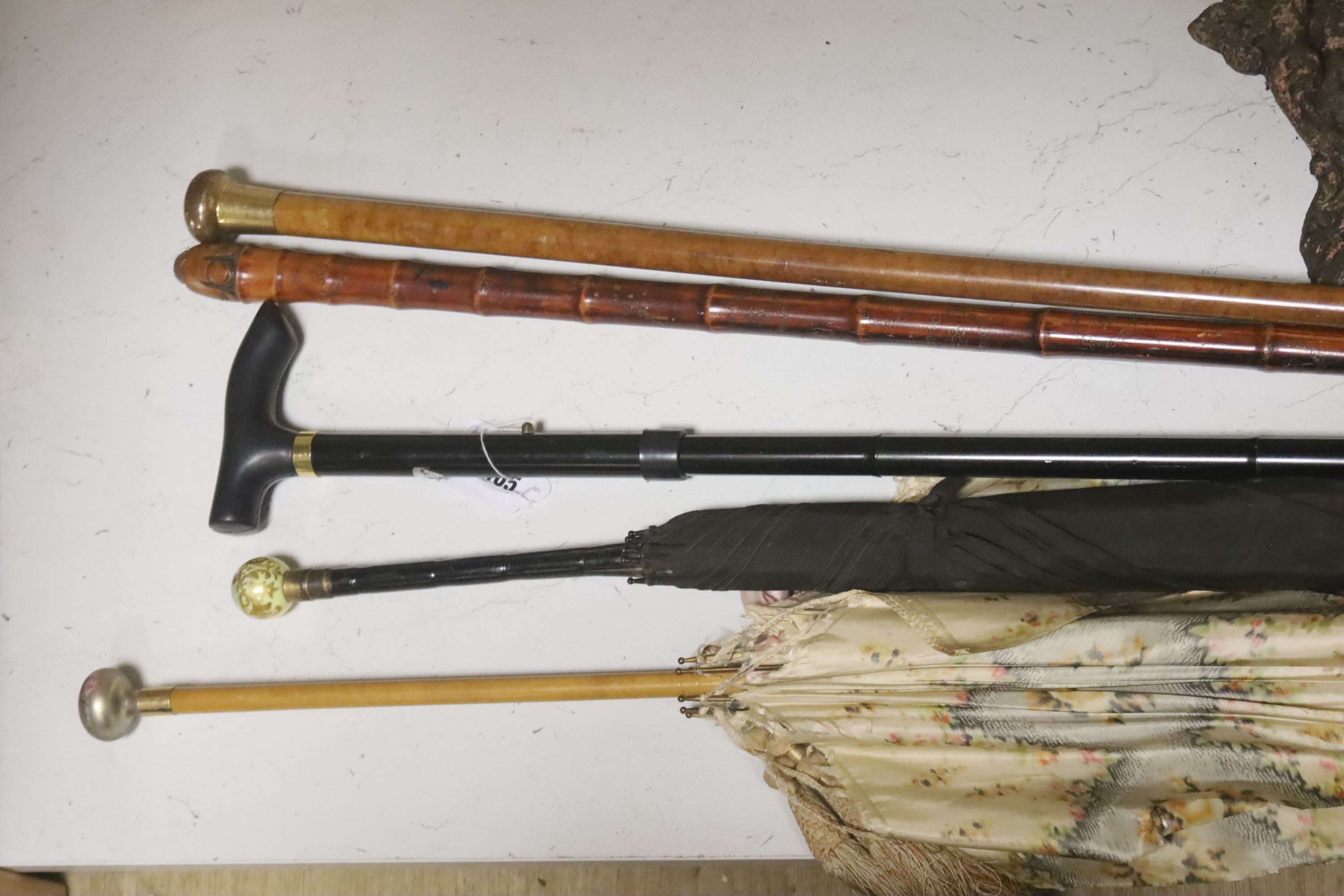 A Chinese bamboo walking stick, two parasols and another stick